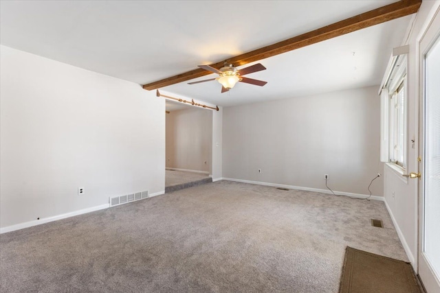 unfurnished room with visible vents, beamed ceiling, and carpet flooring