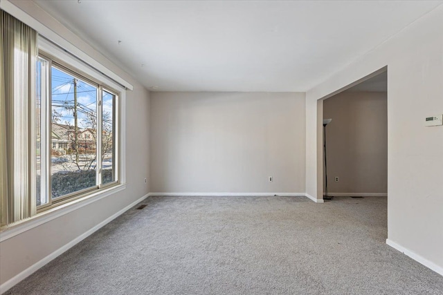 unfurnished room with visible vents, baseboards, and light colored carpet