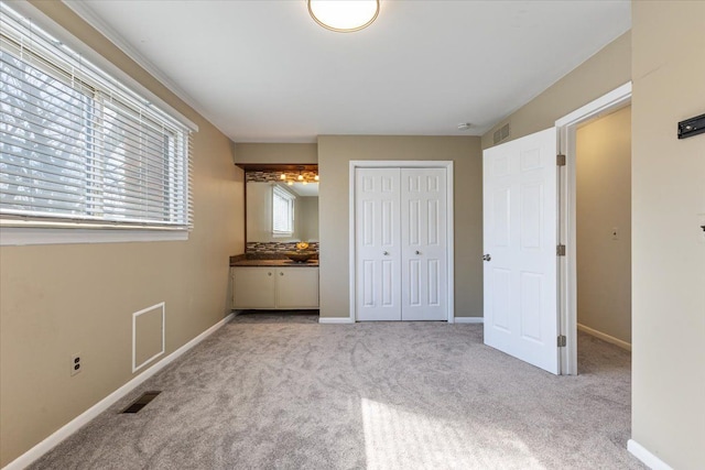 unfurnished bedroom with baseboards, a closet, visible vents, and light colored carpet