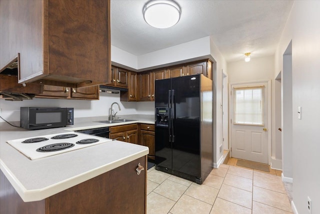 kitchen featuring a peninsula, light countertops, dark brown cabinets, black appliances, and a sink