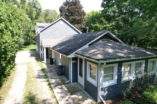 view of side of property with roof with shingles and driveway