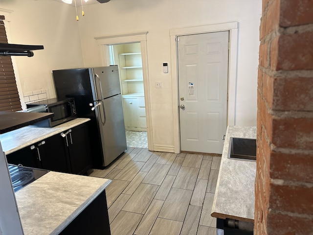 kitchen featuring wood tiled floor, ceiling fan, light countertops, appliances with stainless steel finishes, and dark cabinets