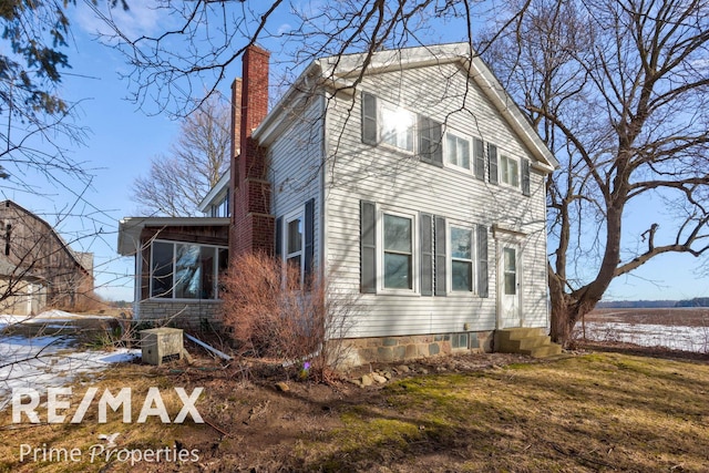 view of home's exterior featuring entry steps, a chimney, and a sunroom