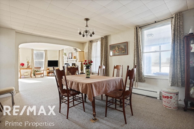 dining room featuring carpet floors, an inviting chandelier, arched walkways, and baseboard heating