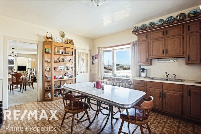 kitchen featuring arched walkways, light countertops, a sink, and dark colored carpet