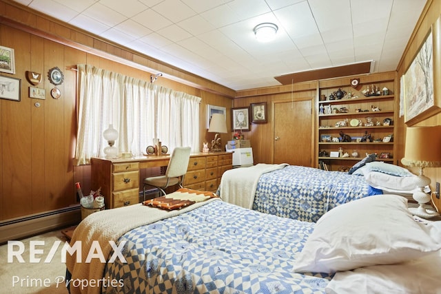 bedroom featuring wood walls and a baseboard heating unit