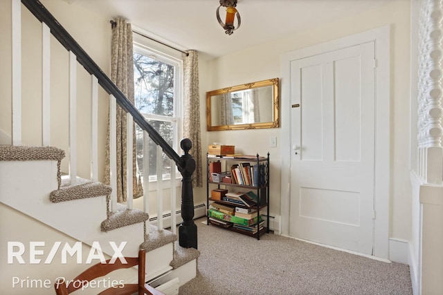 entrance foyer featuring carpet, stairs, a baseboard heating unit, and baseboards