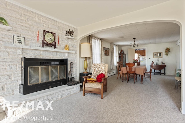 living room with a baseboard heating unit, a fireplace, arched walkways, and a chandelier