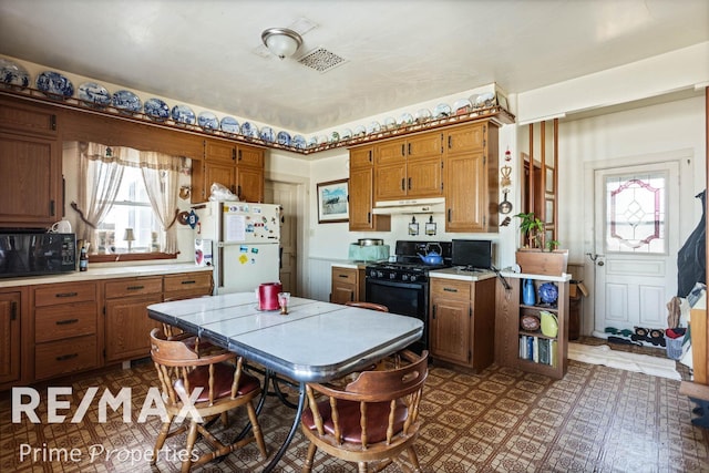 kitchen with black appliances, light countertops, a wealth of natural light, and under cabinet range hood