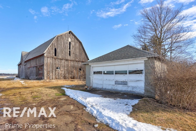 exterior space with a barn, a detached garage, a gambrel roof, and an outbuilding