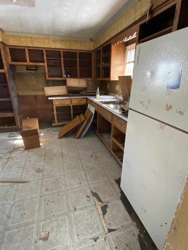 kitchen featuring light floors, a sink, and freestanding refrigerator