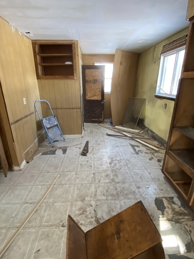 empty room with a healthy amount of sunlight, light floors, and wood walls