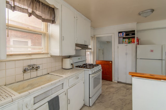 kitchen with tile countertops, white appliances, white cabinets, and under cabinet range hood