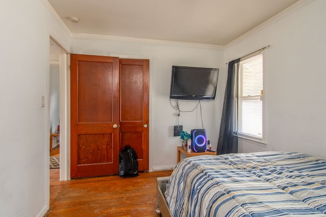 bedroom featuring baseboards, wood finished floors, and crown molding