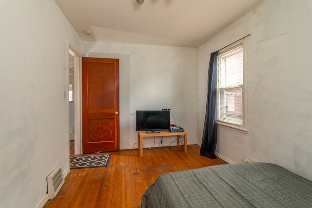 bedroom with baseboards, visible vents, and hardwood / wood-style floors