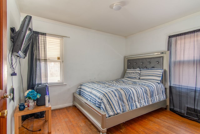 bedroom featuring visible vents, ornamental molding, hardwood / wood-style flooring, and baseboards