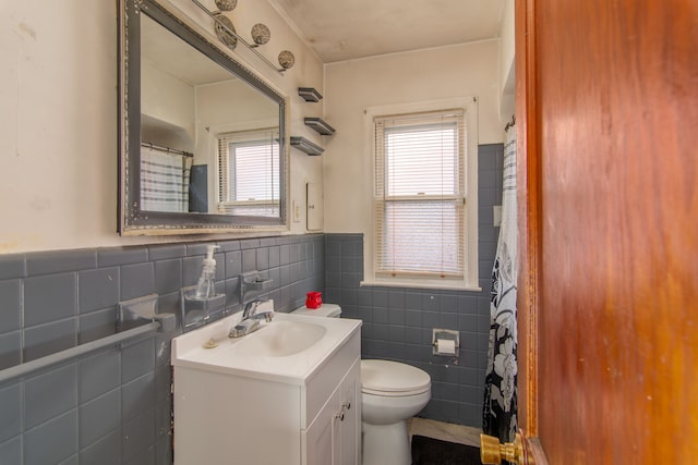 full bath featuring a wainscoted wall, tile walls, toilet, vanity, and a shower with curtain