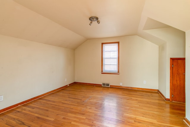 additional living space featuring lofted ceiling, baseboards, visible vents, and light wood finished floors