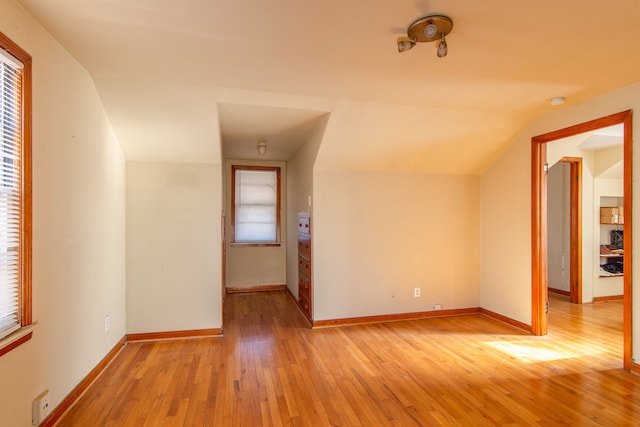 bonus room with vaulted ceiling, light wood-style flooring, and baseboards