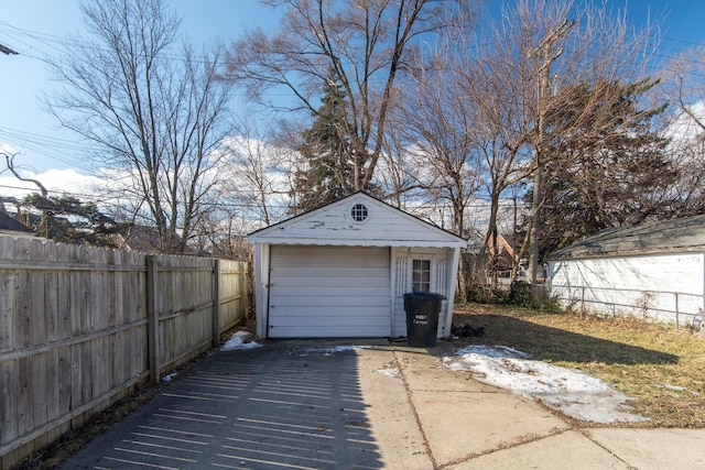 garage with concrete driveway and fence