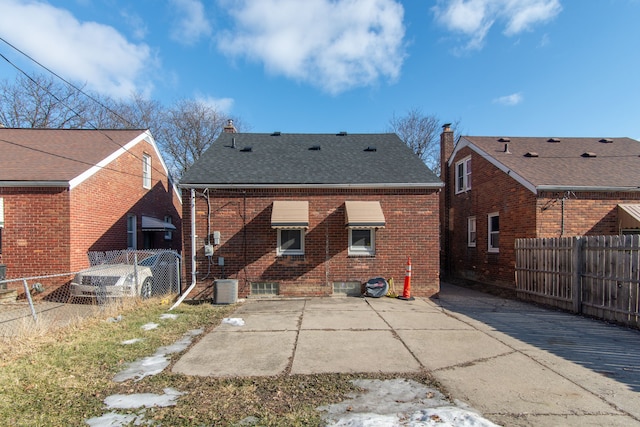 rear view of house with brick siding, a shingled roof, fence private yard, and central air condition unit