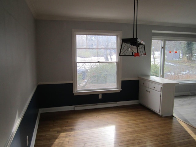 unfurnished dining area featuring a baseboard heating unit, plenty of natural light, light wood-style flooring, and ornamental molding