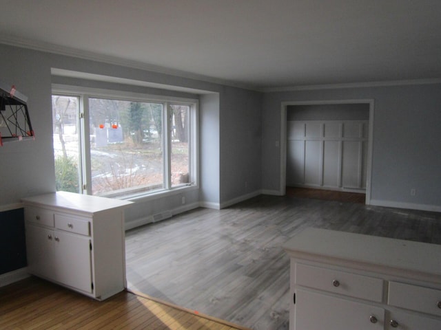 interior space featuring light wood-style flooring, multiple windows, baseboards, and crown molding