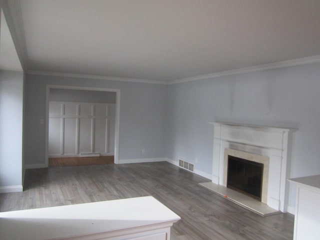 unfurnished living room with a fireplace, visible vents, baseboards, ornamental molding, and dark wood finished floors