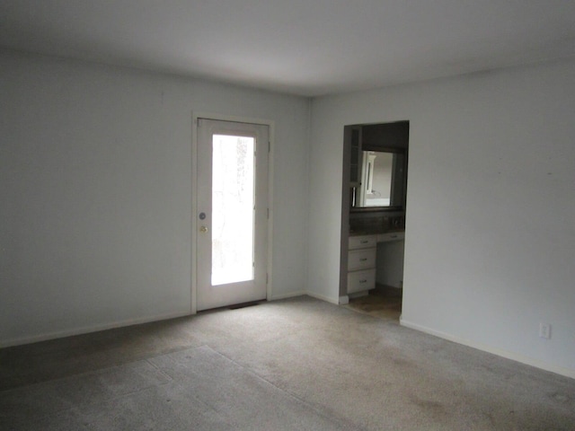 spare room featuring baseboards and light colored carpet