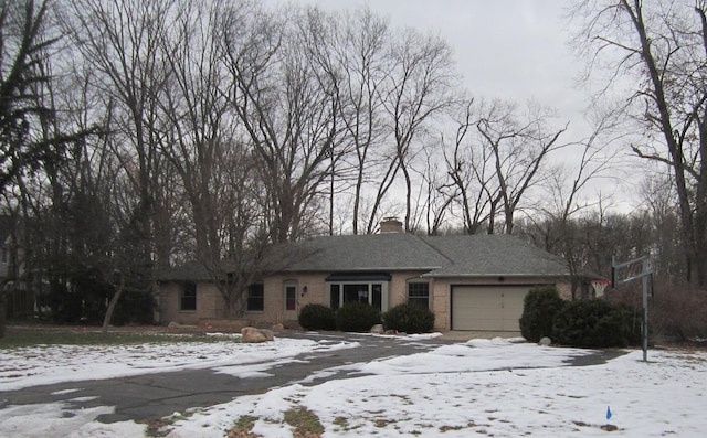 ranch-style home featuring a garage, brick siding, and a chimney