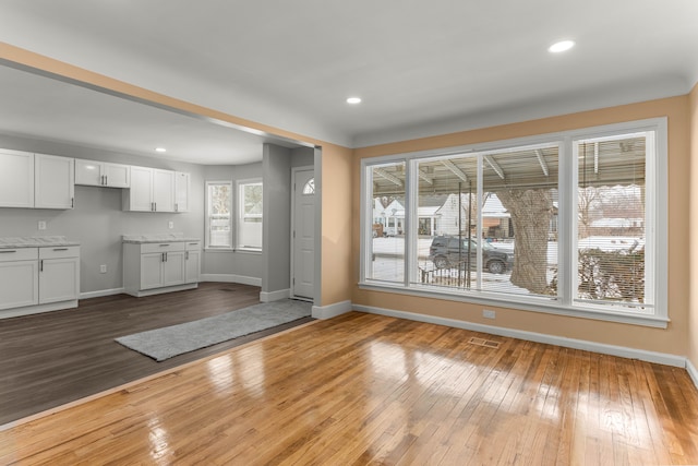 unfurnished dining area with recessed lighting, wood finished floors, visible vents, and baseboards