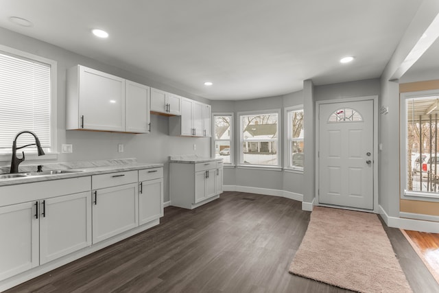 kitchen featuring dark wood-style floors, white cabinetry, a sink, and baseboards