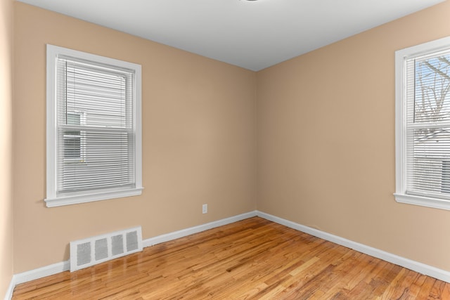 empty room featuring light wood finished floors, visible vents, and baseboards