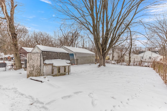 snowy yard with a garage and fence