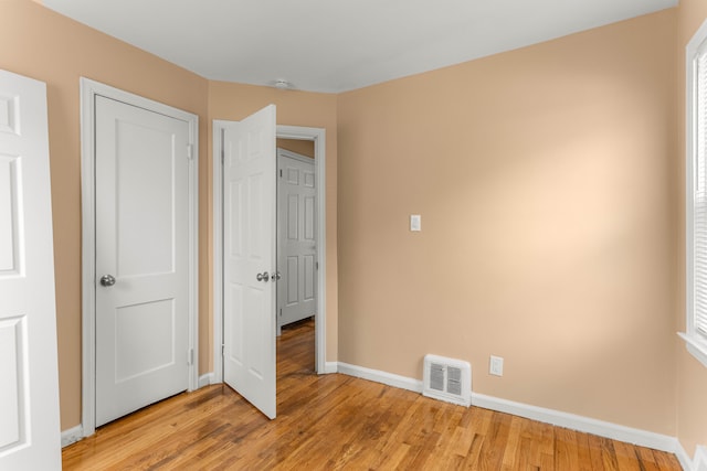 unfurnished bedroom featuring baseboards, visible vents, and light wood-style floors