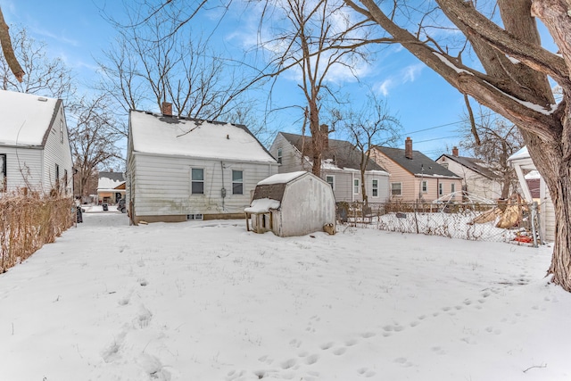 snow covered house featuring a residential view, fence, and a chimney