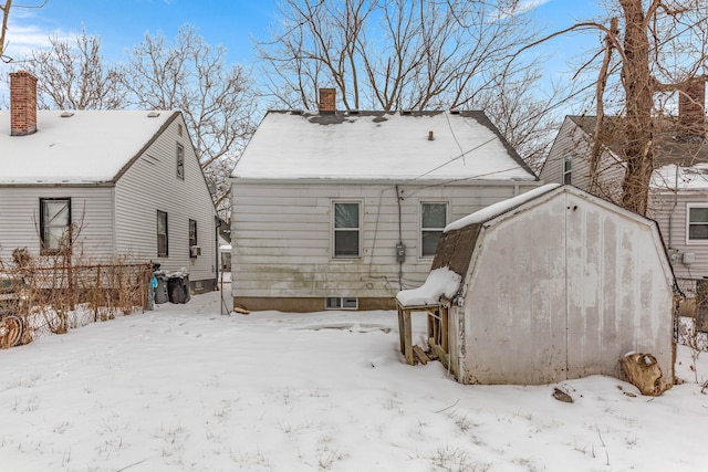 snow covered back of property featuring a garage and a chimney