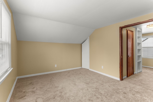 additional living space with light carpet, baseboards, and a healthy amount of sunlight