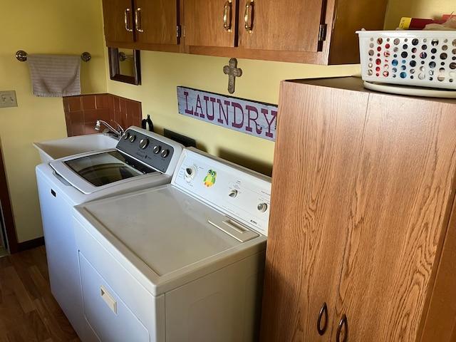 laundry area featuring dark wood finished floors, independent washer and dryer, a sink, and cabinet space