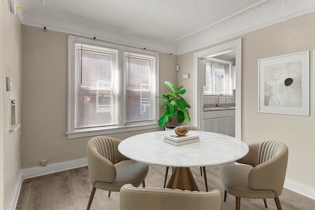 dining area with a healthy amount of sunlight, a textured ceiling, baseboards, and wood finished floors