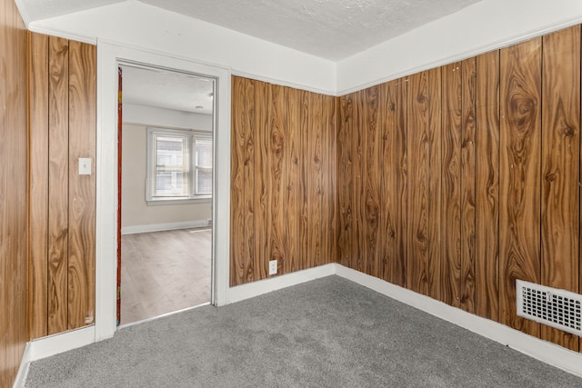 carpeted empty room with baseboards, visible vents, and a textured ceiling