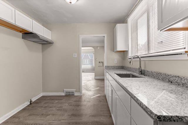 kitchen with dark wood-style floors, a sink, white cabinetry, and baseboards