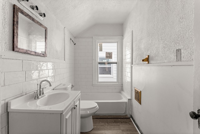 bathroom featuring a tub to relax in, tile walls, toilet, a textured ceiling, and wood finished floors