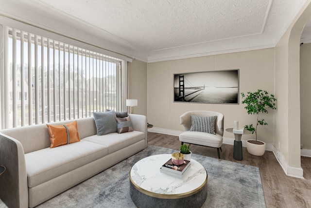 living room featuring a textured ceiling, arched walkways, wood finished floors, and baseboards