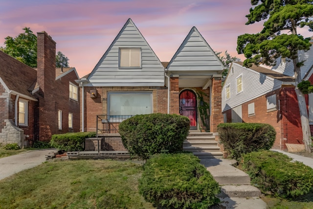 view of front of property with a lawn and brick siding