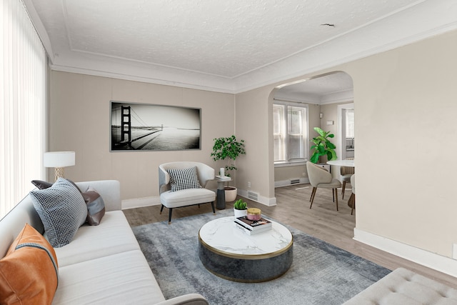 living room with baseboards, arched walkways, visible vents, wood finished floors, and a textured ceiling