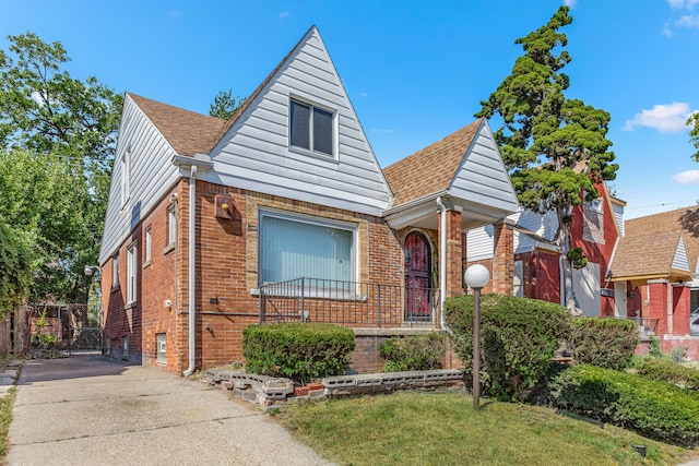 bungalow-style home featuring a shingled roof, a front yard, and brick siding