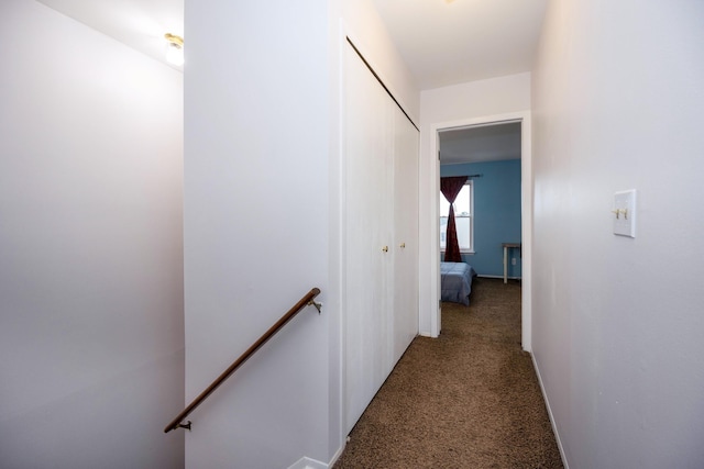 hall with carpet flooring, an upstairs landing, and baseboards