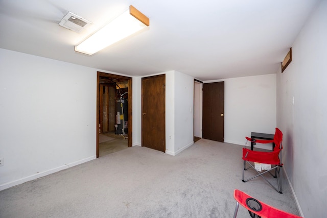 unfurnished room with water heater, visible vents, and baseboards