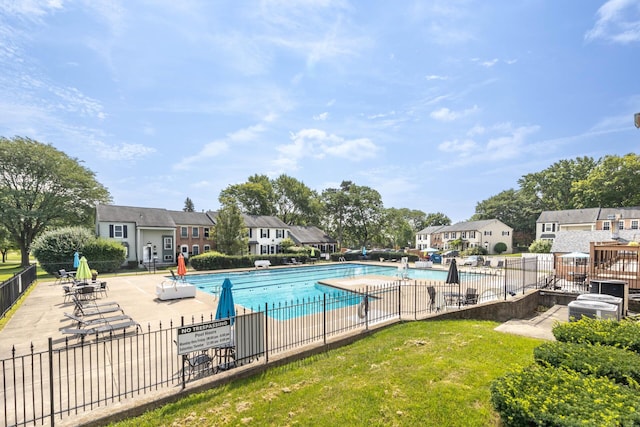 community pool with a residential view, fence, and a patio